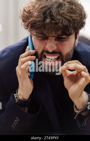 Male student arguing on phone while attending classes at college. Angry student arguing on phone. Stock Photo