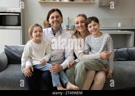 Joyful parents holding daughter and son kid on laps Stock Photo