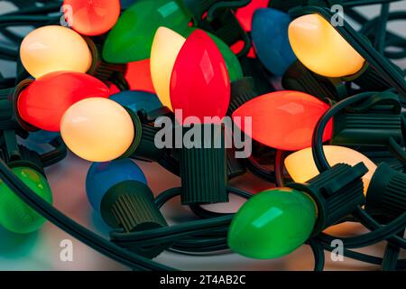 Tangled Christmas string lights turned on and isolated on white background. Holiday decoration safety and lighting concept. Stock Photo