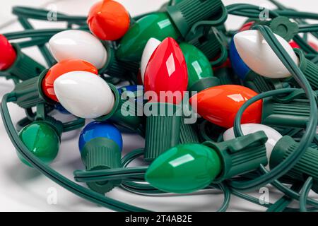 Tangled Christmas string lights isolated on white background. Holiday decoration safety and lighting concept. Stock Photo