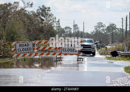 Flooded street in Florida after hurricane rainfall with road closed signs blocking driving of cars. Safety of transportation during natural disaster Stock Photo