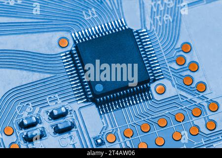 Chip in QFP package on blue printed circuit board. Technologies and microelectronics. Macro photography Stock Photo