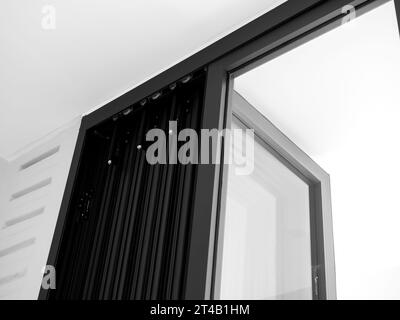 Close-up door hinges on the black aluminum folding doors with glass on white building background, indoor and outdoor partition, interior doorway decor Stock Photo