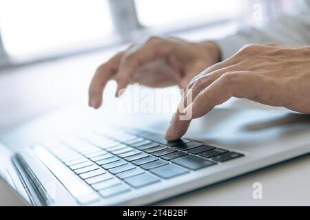 Closeup of businessman's hands typing on a laptop computer for data input and analysis in business performance and investment Stock Photo