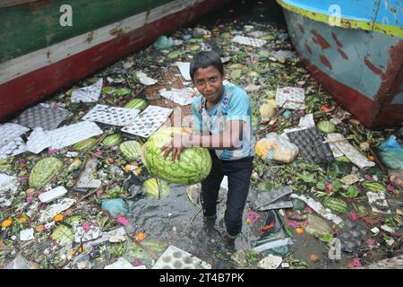 Dhaka Bangladesh march24 2023, A boy collected discar desd watermelon in the dirty water of buriganga river at sadarghat launch Terminal dhaka . Nazmul islam/alamy live news. Stock Photo