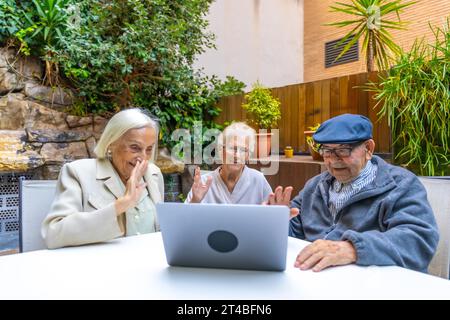 Introducing technology to senior people in a nursing home while three people using laptop Stock Photo