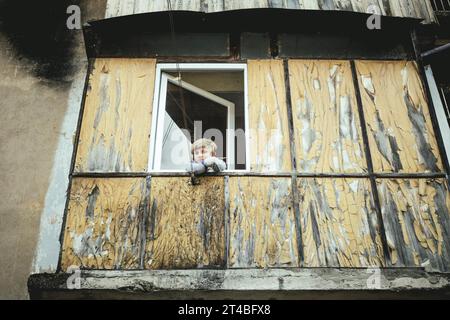 A boy looks out of the window of a flat of a building in danger of collapsing in Akarmara, Akamara, Abkhazia, Georgia Stock Photo