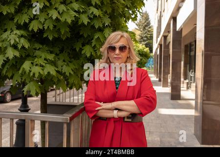 Portrait Posing Business Lady, Mature Sexagenarian Woman Outdoor in Summer Time, City, Stylish Confident Senior Female in her 60s Wears Sunglasses Stock Photo