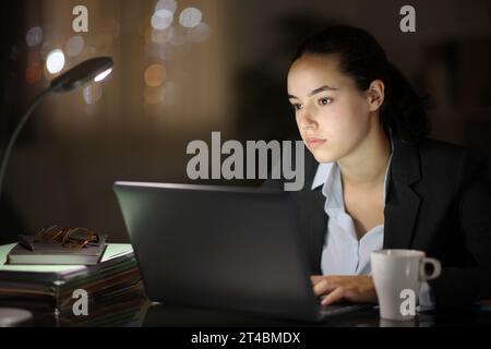 Serious distracted businesswoman working in the night looking away Stock Photo