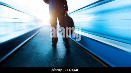 Business people walking at moving escalator in airport Stock Photo