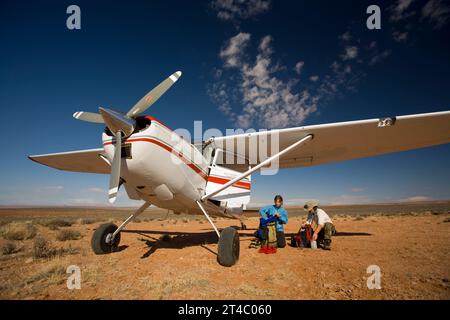Man and woman next to small plane in desert getting ready to go hiking, Utah. Stock Photo