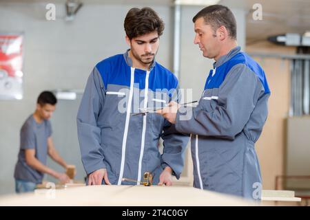 carpentry teacher giving advice to apprentice Stock Photo