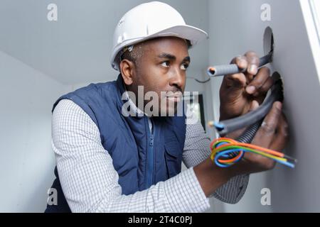 worker trying to install wires on the wall Stock Photo