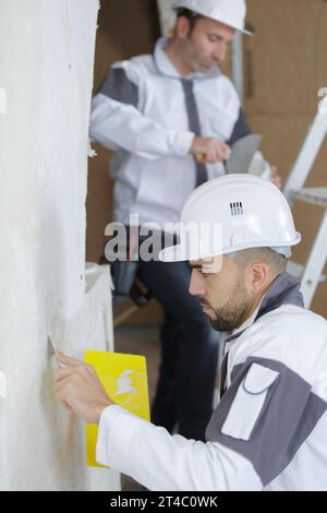 plasterers applying the plaster on the wall with a spatula Stock Photo