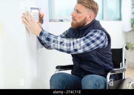 disabled male electrician installing security system Stock Photo
