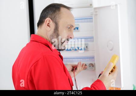 electrician measuring voltage in distribution board Stock Photo