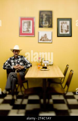 A portrait of a Latinoamerican man and his cowboy hat in a restaurant. Stock Photo