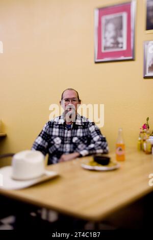 A portrait of a Latinoamerican man and his cowboy hat in a restaurant. Stock Photo