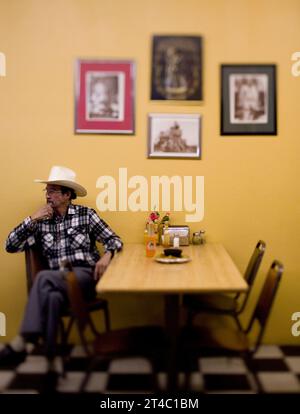 A portrait of a Latinoamerican man and his cowboy hat in a restaurant. Stock Photo