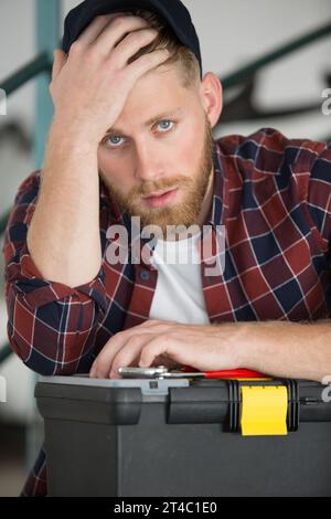 stressed tradesman leaning on his toolbox Stock Photo