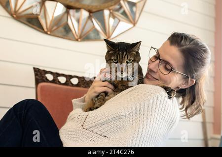 Women holding pet cat looking and smiling at him Stock Photo