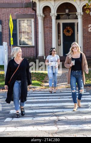 three women walking across the street on a crosswalk Stock Photo