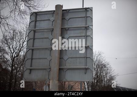 Road sign at the back. A pole with a sign on the reverse side. The design of the road sign. Steel shield. Stock Photo