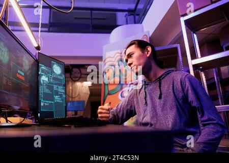 Sad hacker failing to pass security system while cracking password unsuccessfully. Upset asian man getting access denied while hacking online database server in abandoned warehouse Stock Photo