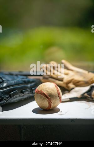 Old baseball ball, mitt and batting gloves siting on the dirty windowsill with copy space Stock Photo