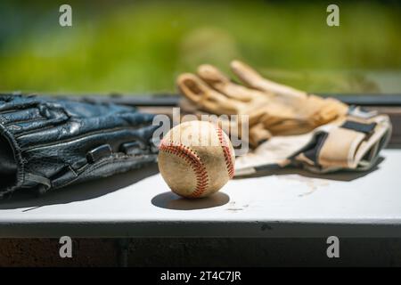 Old baseball ball, mitt and batting gloves siting on the dirty windowsill with copy space Stock Photo