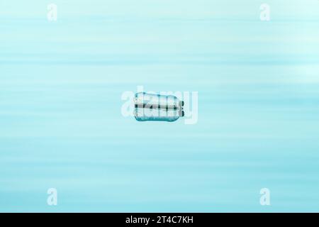 Empty plastic bottle floating on water, environmental damage and pollution concept, selective focus Stock Photo