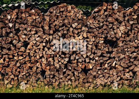 Large stack of chopped firewood on farmland drying in summer, selective focus Stock Photo