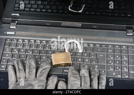 hands with gloves typing on laptop keyboard with safety lock, privacy, thefts of data Stock Photo