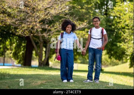Smiling boy and girl walking hand in hand in the park Stock Photo