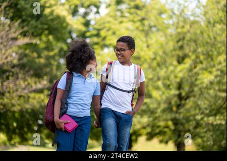 Smiling boy and girl walking hand in hand in the park Stock Photo