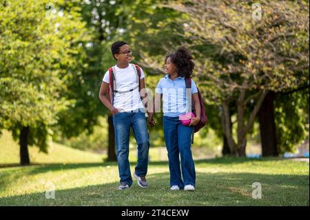 Smiling boy and girl walking hand in hand in the park Stock Photo
