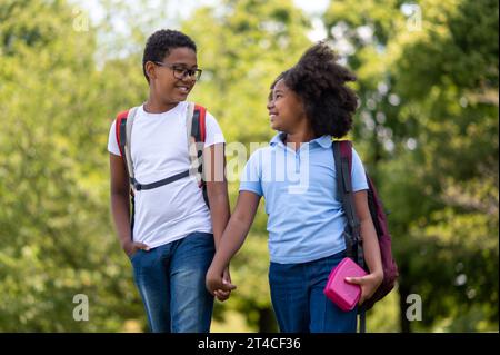 Smiling boy and girl walking hand in hand in the park Stock Photo