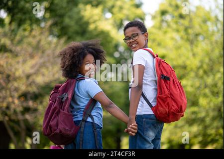 Smiling boy and girl walking hand in hand in the park Stock Photo