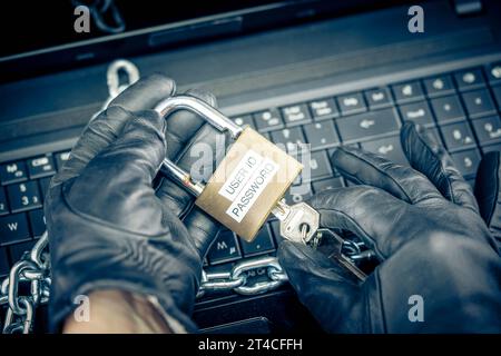 hands with gloves typing on laptop keyboard with padlock, cyberattack Stock Photo