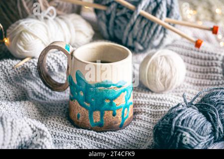 Cozy composition with a cup of coffee, threads and a knitted element. Stock Photo