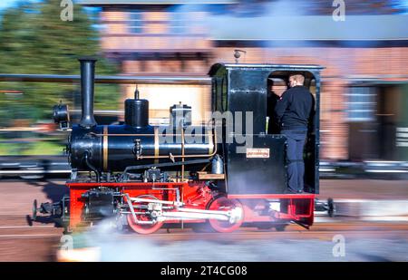 30 October 2023, Mecklenburg-Western Pomerania, Klütz: The small steam locomotive with 20 hp of the company Orenstein & Koppel from the year of construction 1921 is shunted in front of the passenger train in the station. (long exposure shot) The locomotive pulls a passenger train over the 'Kaffeebrenner' narrow-gauge railway line. At the end of the season on the tourist railroad with 600 millimeters gauge, the route is driven by a historic steam steed. Photo: Jens Büttner/dpa Stock Photo