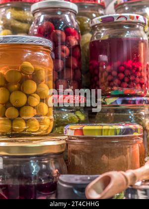 Assorted fruit and vegetable preserves in jars stacked on kitchen tabletop Stock Photo