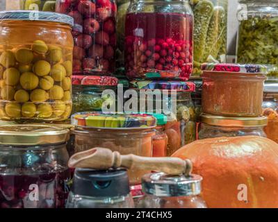 Assorted fruit and vegetable preserves in jars stacked on kitchen tabletop Stock Photo