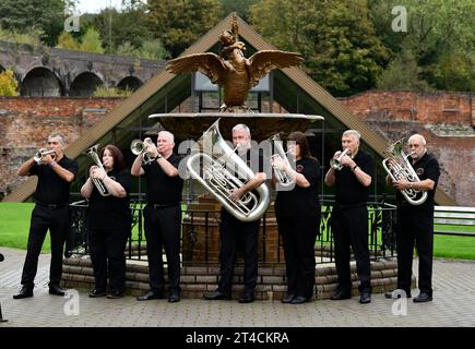 Members of Jackfield Band and the Boy and Swan cast iron water fountain at Coalbrookdale Museum of Iron. The site is the venue of Brass Band Festival Stock Photo