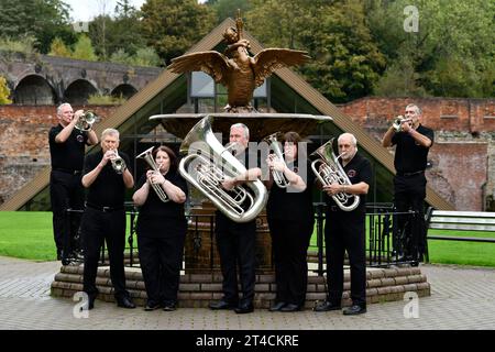 Members of Jackfield Band and the Boy and Swan cast iron water fountain at Coalbrookdale Museum of Iron. The site is the venue of Brass Band Festival Stock Photo