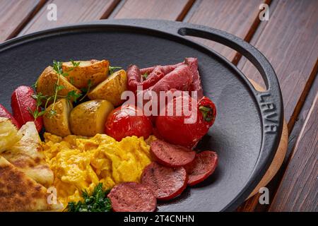Close-up of a plate of fried eggs with bacon, sausage and baked potatoes Stock Photo