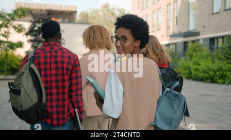 Diverse people group of university friends teens high school pupils multiracial friends classmates students hurry to lesson walking outdoors African Stock Photo