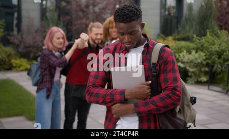 Stressed African American school guy male student bullied man suffer with racism discrimination bullying multiracial students classmates mock Stock Photo