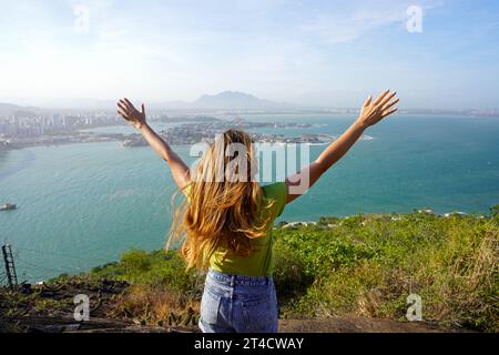 Girl on the mountain peak enjoys the wind on her face. Peaceful woman who appreciates the strength of nature. Stock Photo