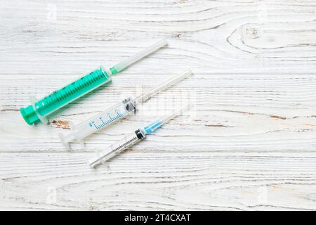 Top view of syringes of different sizes on wooden background. Medical equipment for injection concept with copy space. Stock Photo